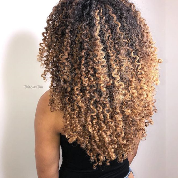 Back of woman’s head with blonde balayage through curly hair, created using Wella Professionals
