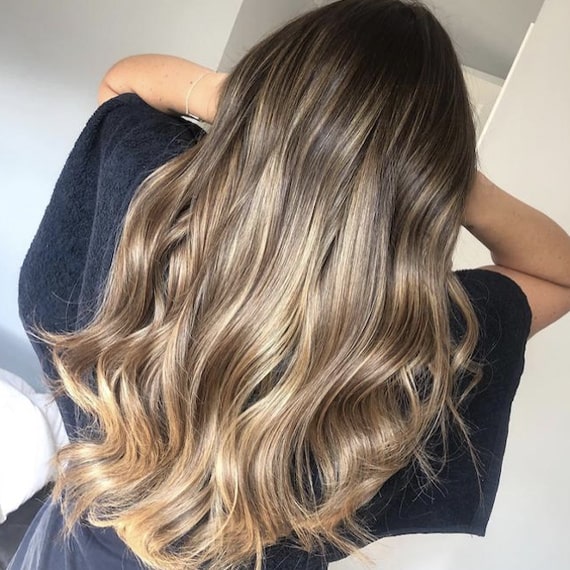 Back of woman’s head with long, wavy, brown blonde balayage, created using Wella Professionals.
