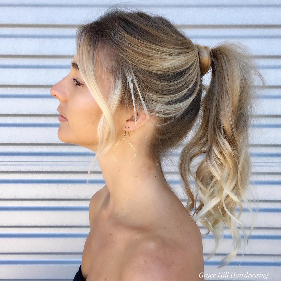 Woman with long golden blonde hair, styled in a ponytail with loose waves