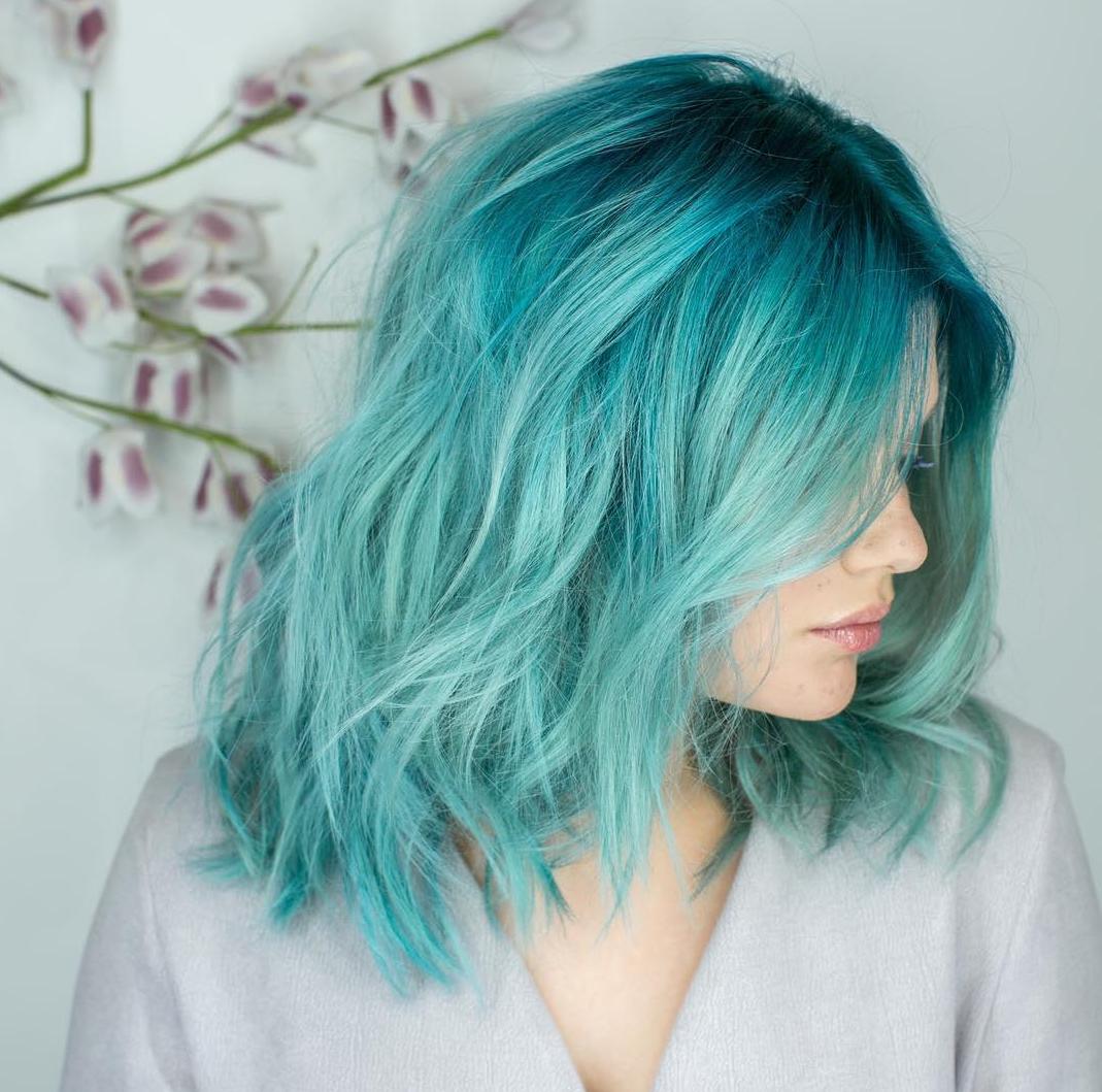 Woman with short, aqua blue hair with loose waves