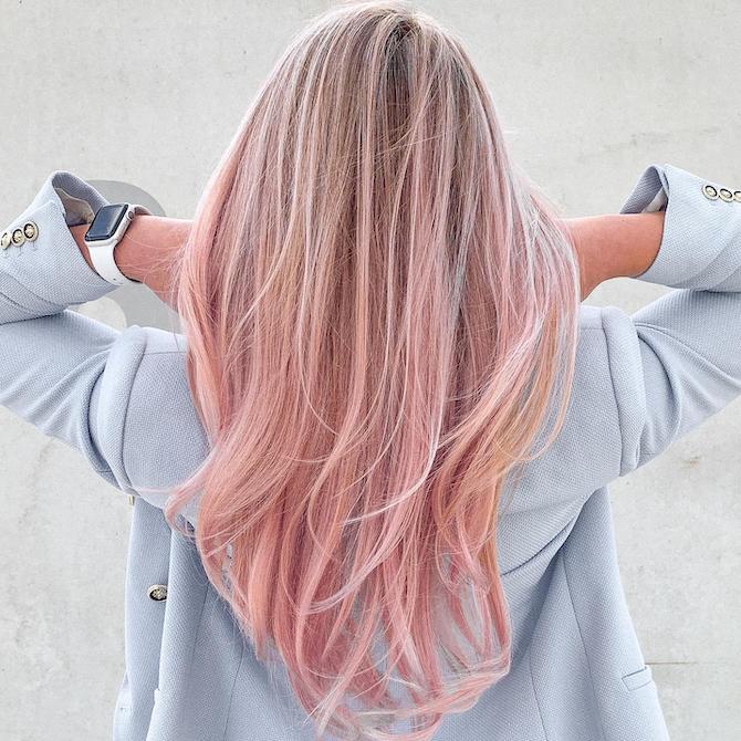 Back of woman’s head with long, blonde hair and pastel pink balayage.