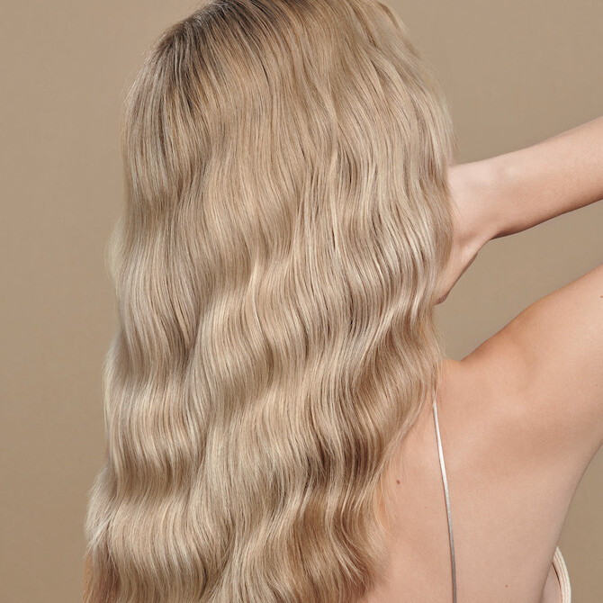 Back of model’s head with long, wavy, cool blonde hair.