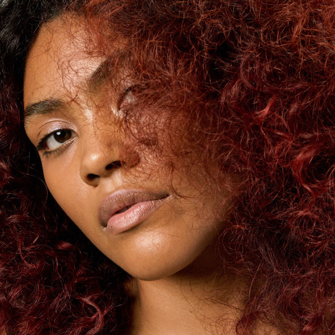Close-up of model with cherry chocolate, curly hair.