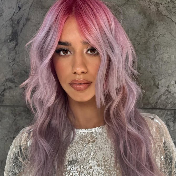 Model with pink to purple ombre hair styled in loose waves.