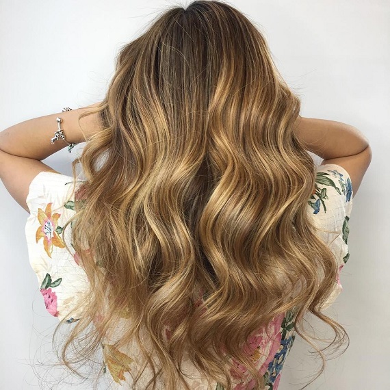 Back of woman’s head with long, wavy, golden toffee hair, created using Wella Professionals. 