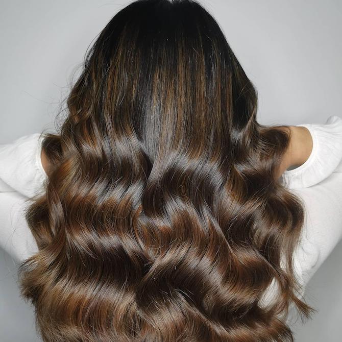 Back of woman’s head with long, loosely curled, mocha brown hair, created using Wella Professionals. 