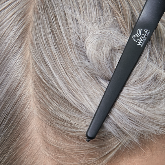 Close-up of grey hair sectioned off with a Wella Professionals clip.