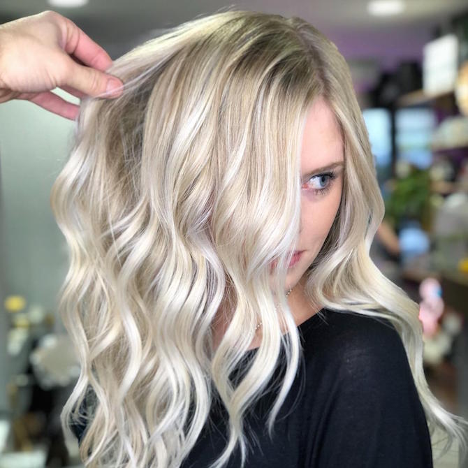 Woman having blonde, wavy hair styled in a Wella Professionals salon.