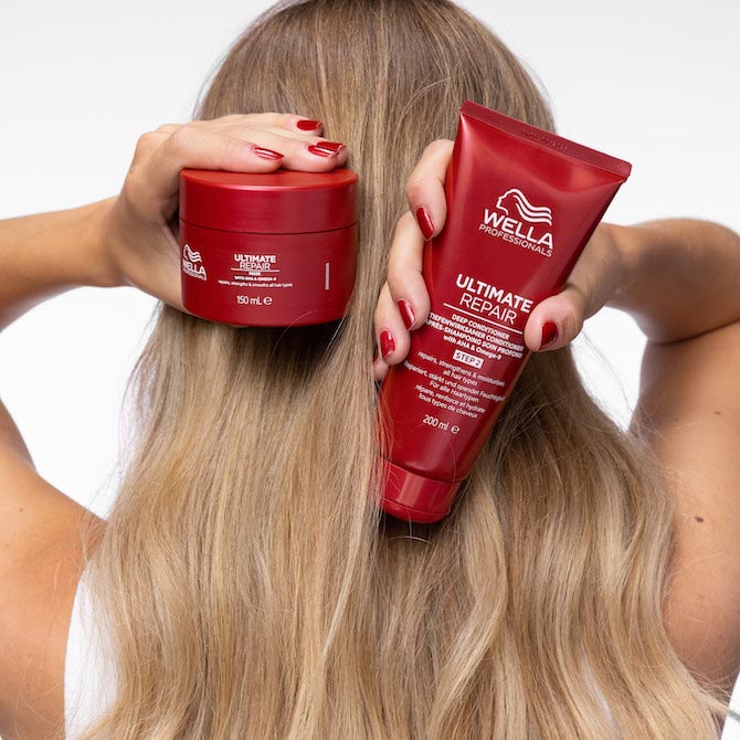 Hinterkopf eines Models mit langem, glattem, goldblondem Haar. Sie hält die ULTIMATE REPAIR Maske und den Conditioner hoch.