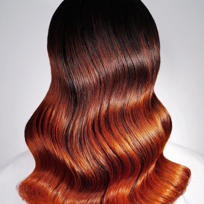 Back of woman’s head with glossy, polished waves and red ombre hair color, created using Wella Professionals.