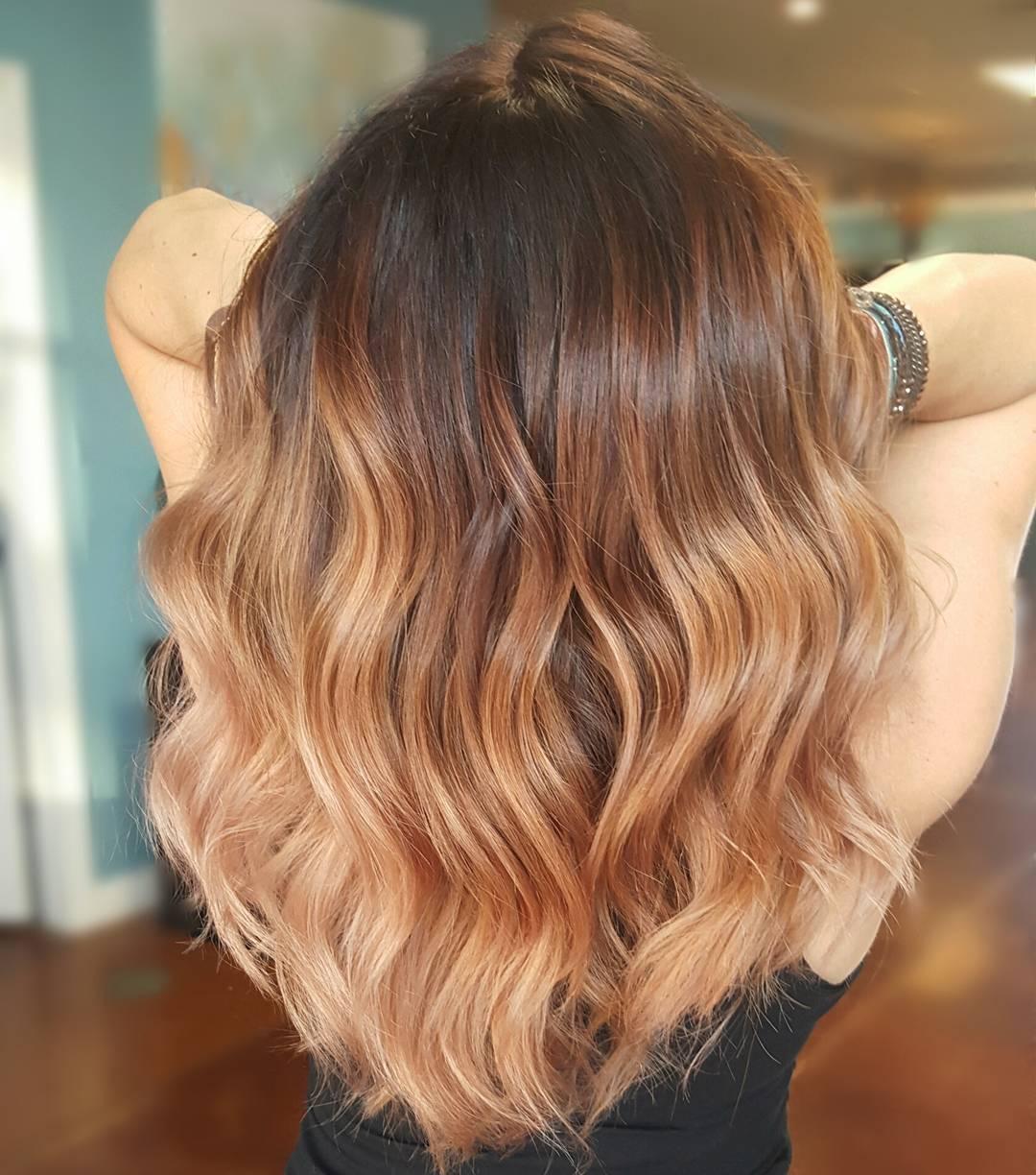 Back of woman's head with dark roots and caramel blonde hair styled with loose waves