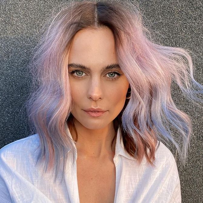 Model with pastel pink hair and powder blue balayage faces camera. 