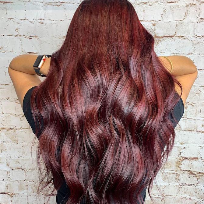 Back of woman’s head with long, wavy, burgundy red hair, created using Wella Professionals.