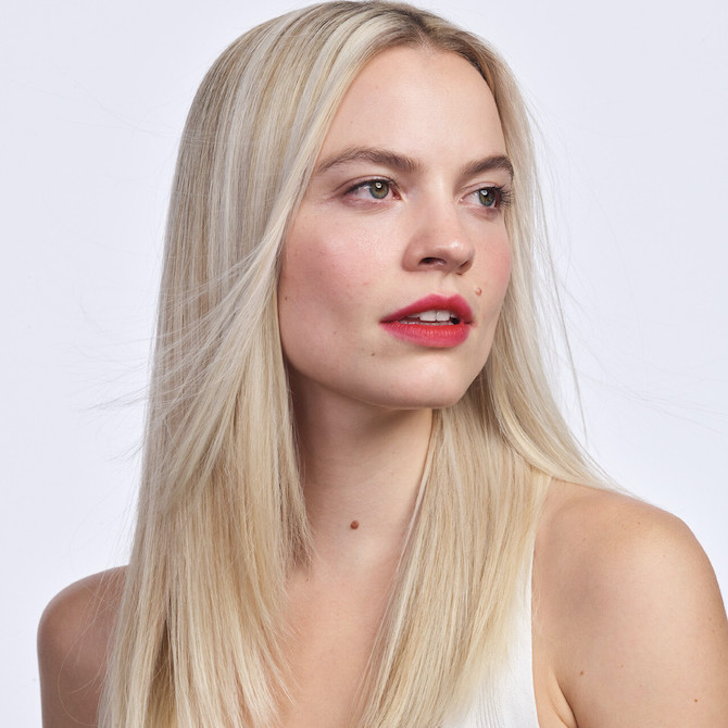 Headshot of a model looking into the distance with straight platinum blonde hair and red lips