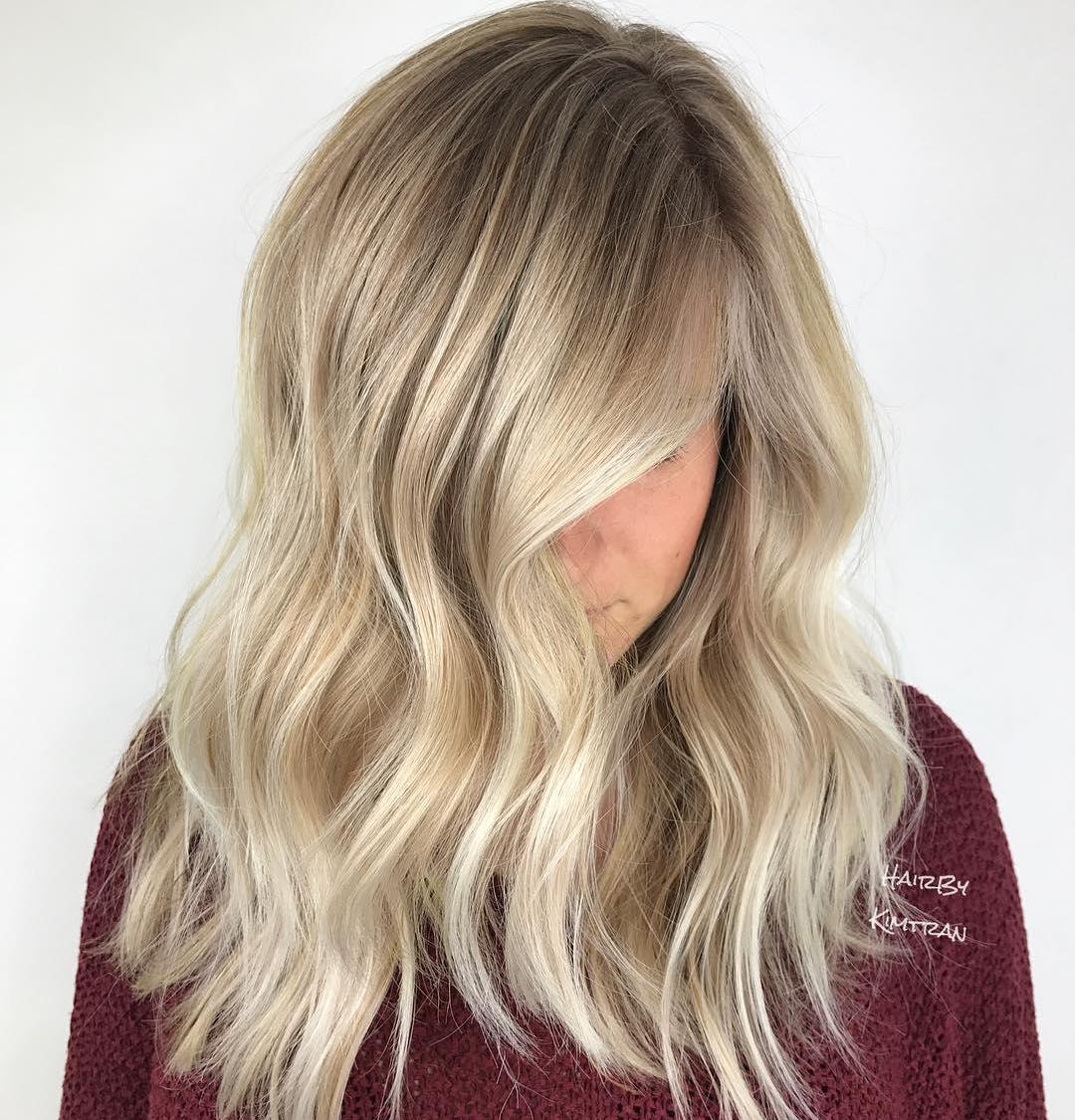 Woman with mid length, beige blonde hair styled with loose waves