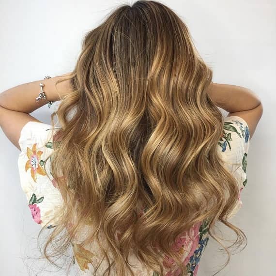 Back of woman’s head with long, wavy, golden toffee hair, created using Wella Professionals.