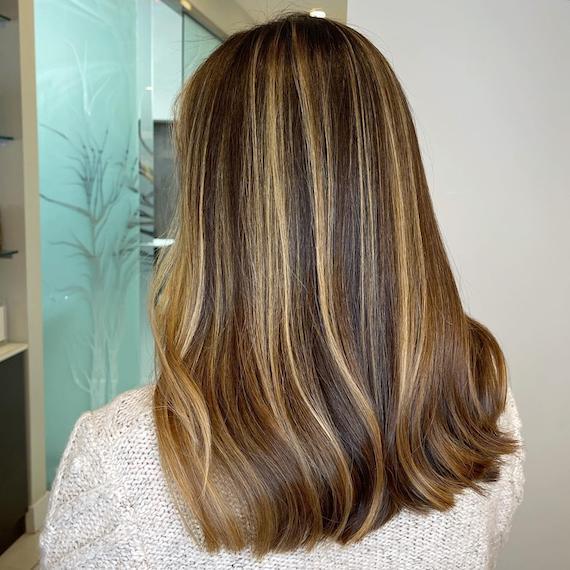 Back of woman’s head with brown hair and blonde chunky highlights, created using Wella Professionals. 