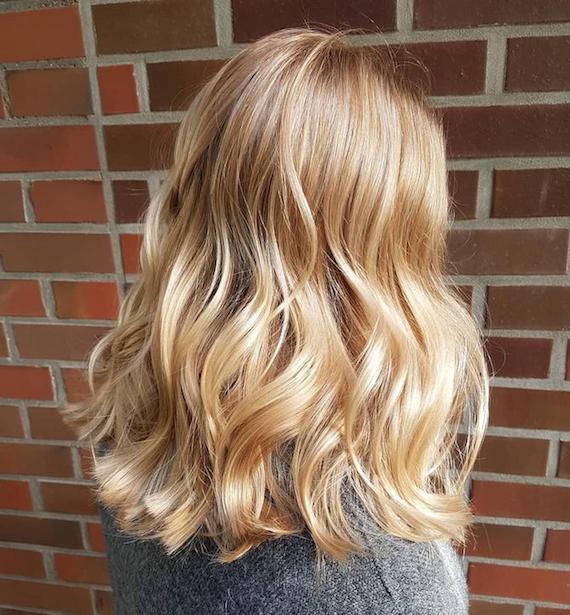 Photo of the back of a woman’s head with wavy golden blonde hair, created using Wella Professionals