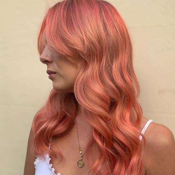 Side profile of woman with tousled bright blorange hair.