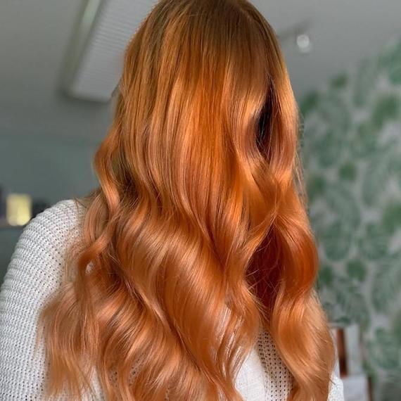 Woman with long, wavy, warm blorange hair falling past her shoulders. 