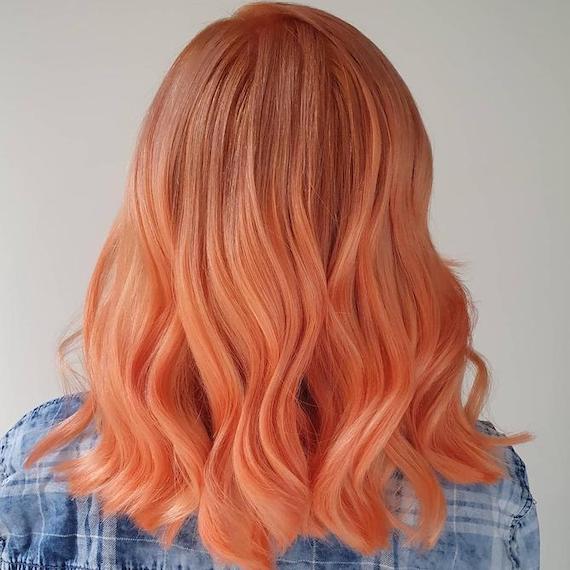 Back of woman’s head with mid-length, sunset blorange hair.