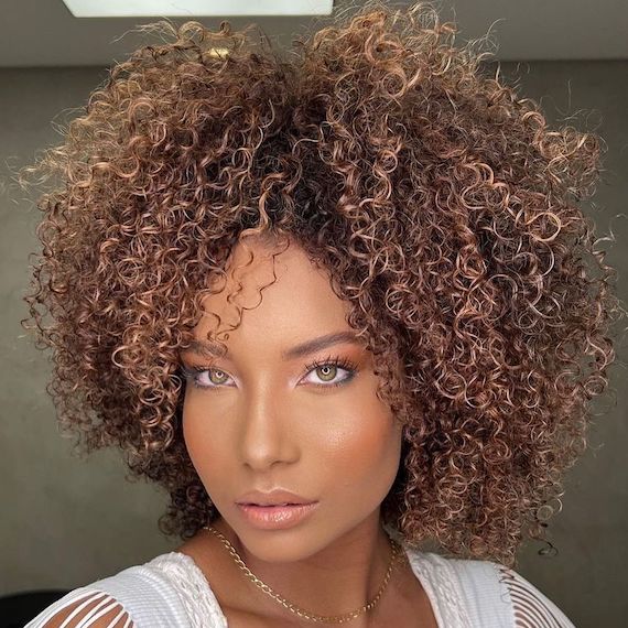 Model faces the camera showing her very defined type 3C curls in light brown color hues