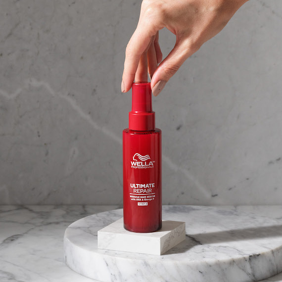 Nahaufnahme einer Hand, die den Deckel einer Flasche von Ultimate Repair Miracle Hair Rescue von Wella Professionals berührt