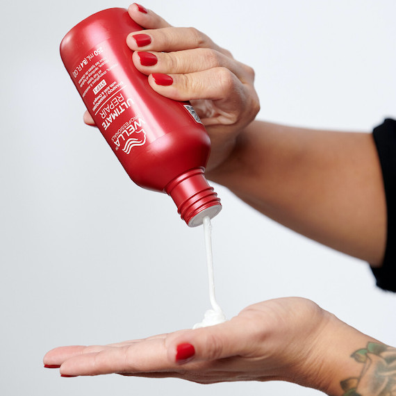 Model pours ULTIMATE REPAIR Shampoo into palm of hand.