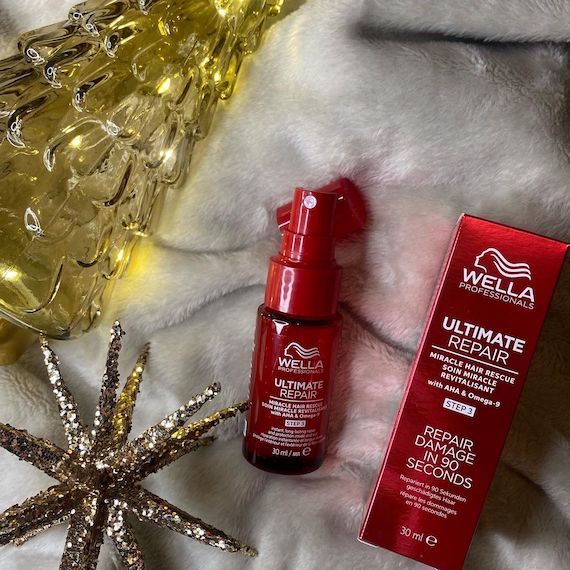 ULTIMATE REPAIR Miracle Hair Rescue next to a lit-up glass holiday tree.