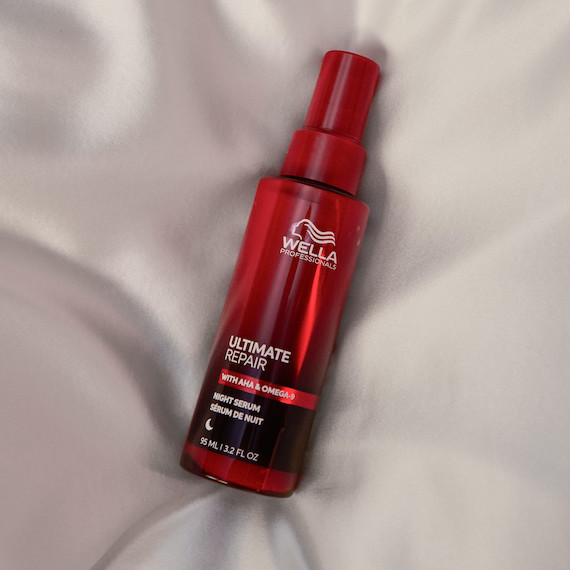 ULTIMATE REPAIR Night Serum on white sheets.