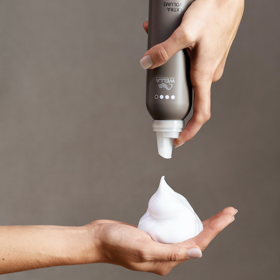 Model squeezes EIMI Extra Volume mousse into palm of hand.