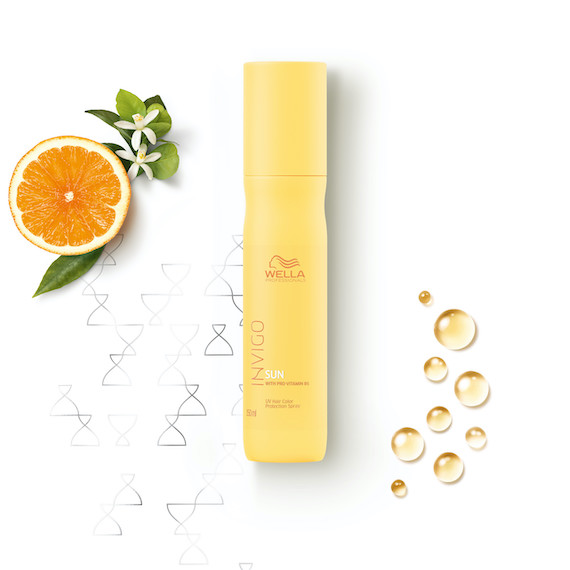 INVIGO Sun Care Leave-In Spray on a white surface next to a slice of orange.