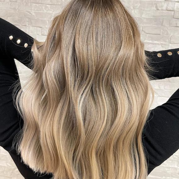 Back of woman’s head with long, tousled, beige neutral blonde hair and balayage.