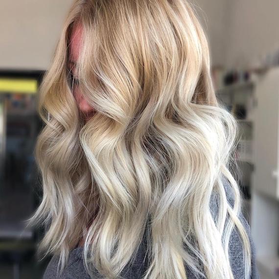 Side profile of woman with creamy neutral blonde balayage through her hair.