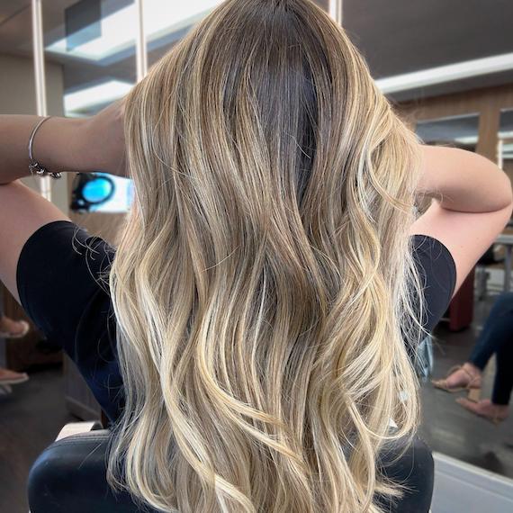 Back of woman’s head with long, beachy, neutral blonde hair and balayage.