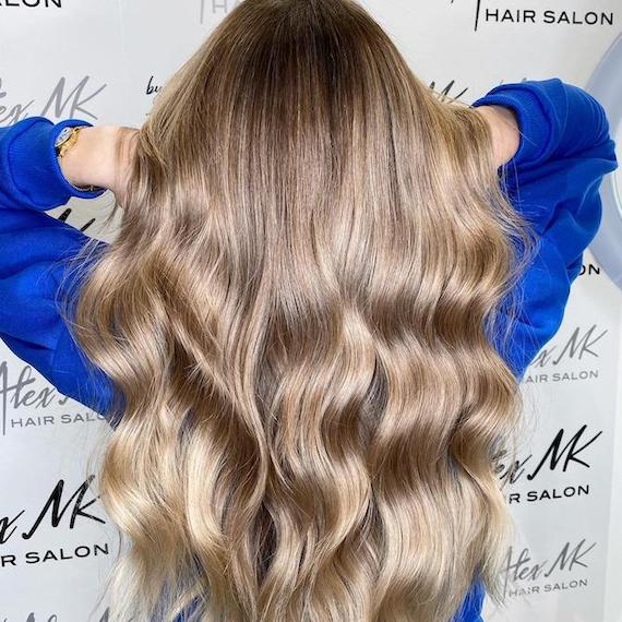 Back of woman’s head with long, wavy, neutral blonde hair created with babylights.