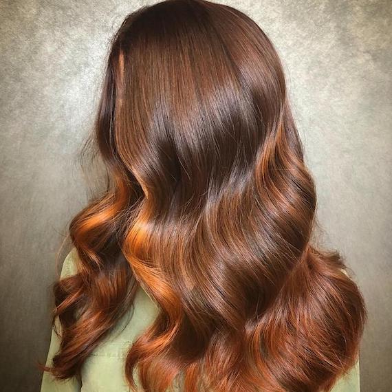 Side profile of woman with rich brown hair and a red money-piece.