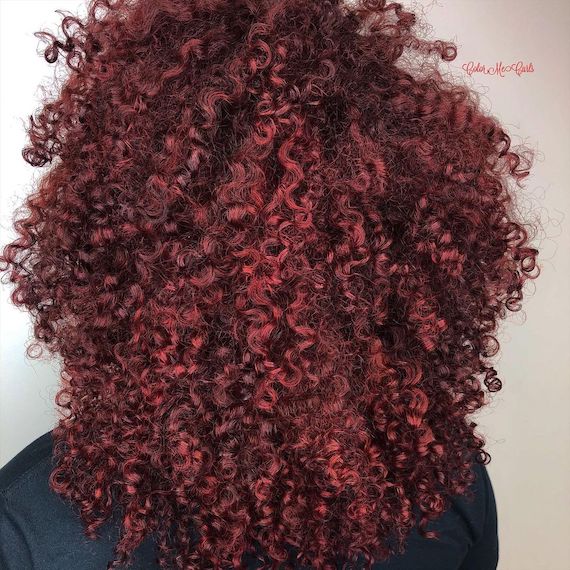Model with cherry cola color through glossy, curly hair. 