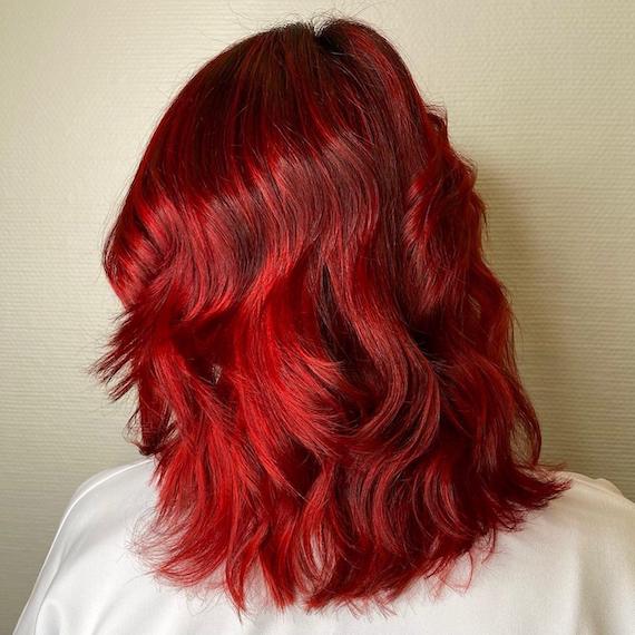 Model with wavy, bright ruby red hair.