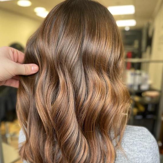 Back of woman’s head with mid-length, tousled, light mocha brown hair.