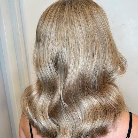 Back of woman’s head with loosely waved, sandy blonde hair, created using Wella Professionals.