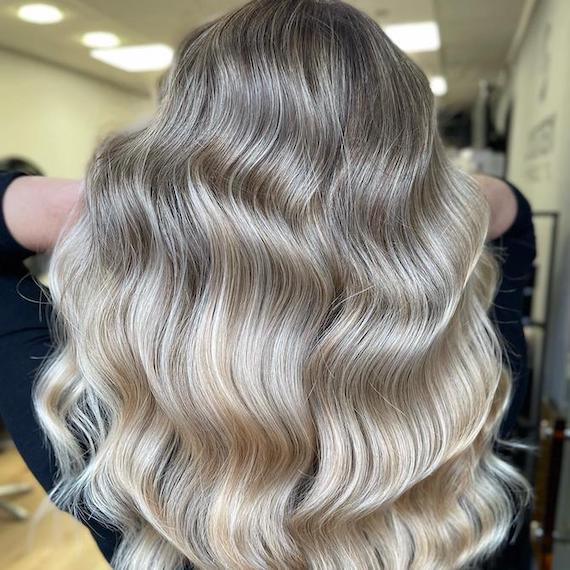 Back of woman’s head with long, wavy, stone blonde hair.