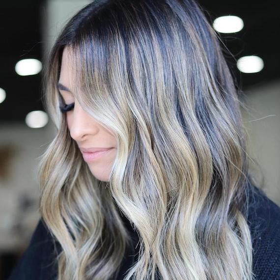 Side profile of woman with tousled, deep rooted, stone blonde hair. 