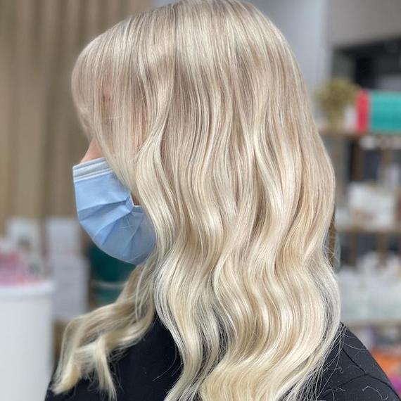 Side profile of woman with wavy, creamy, stone blonde hair.