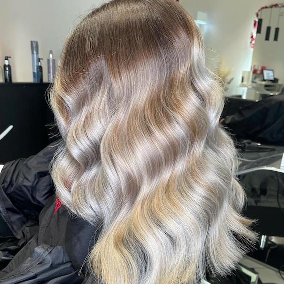 Back of woman’s head with long, wavy, stone blonde ombre hair.