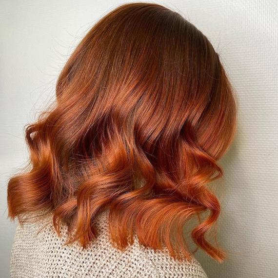 Side profile of woman with copper bob haircut featuring ombre tones.