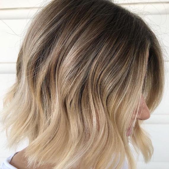 Side profile of woman with wavy, blonde, ombre bob haircut.