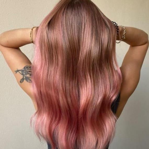 Back of woman’s head with long, wavy hair and pink balayage.