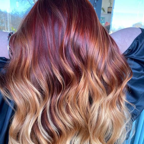 Back of woman’s head with long, wavy, auburn blonde hair.