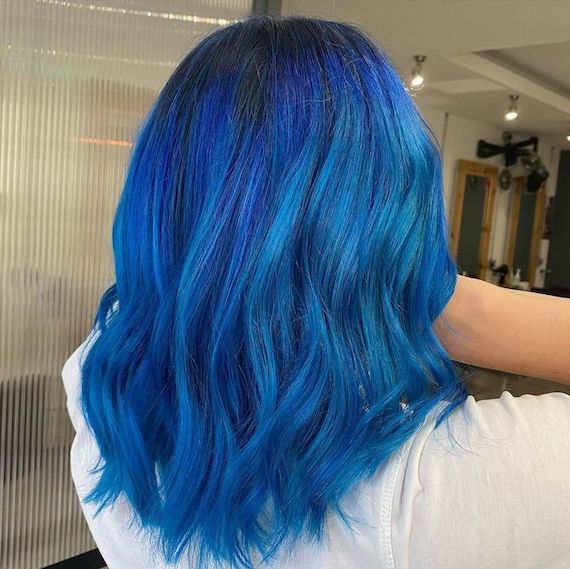 Back of woman’s head with bright blue, wavy hair.